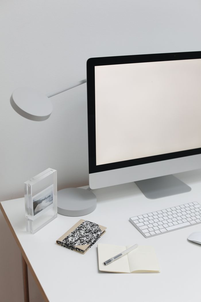 Contemporary workspace with wireless gadgets under monitor and creative picture in room with simple design